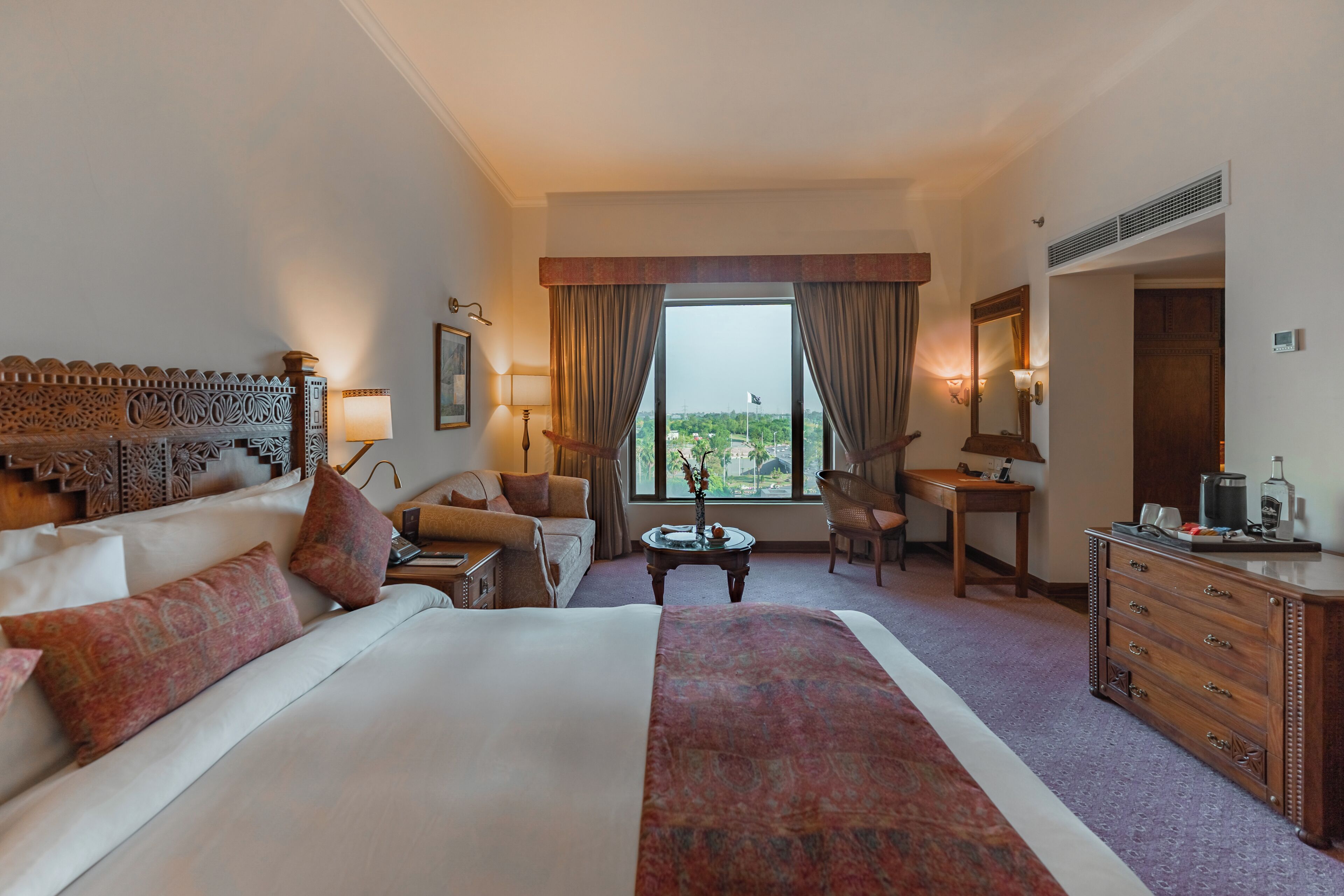 Una habitación de hotel con una cama grande, un sofá, un escritorio y vistas a la ciudad.