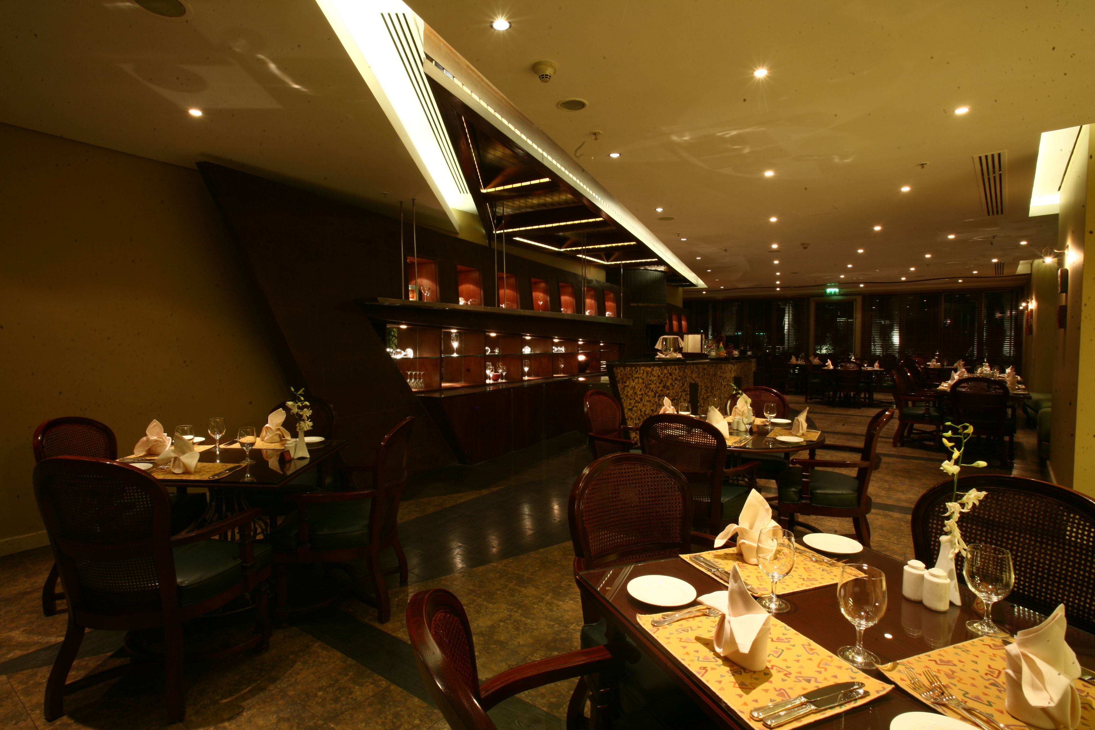 Un restaurante con varias mesas, sillas y una zona de bar.
