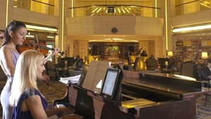 A grand piano in a spacious lobby with a high ceiling and palm trees, suggesting a luxurious setting. - Le Royal Hotel Amman (Amman)