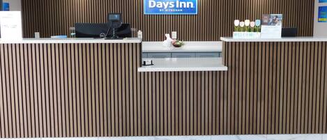 Uma receção com o logotipo Days Inn, um computador e uma placa de boas-vindas.