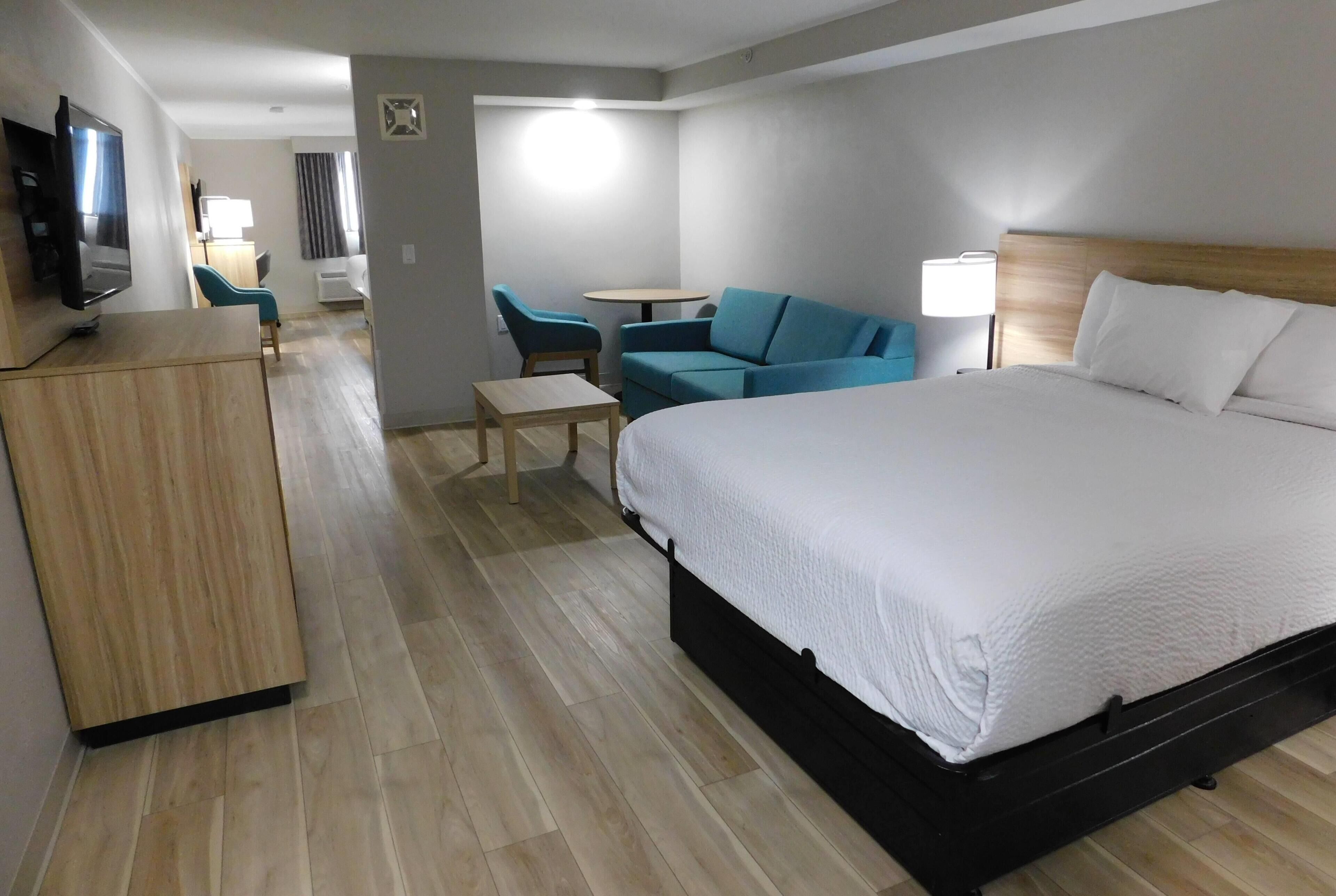 Una habitación de hotel con cama, televisión, escritorio y silla.