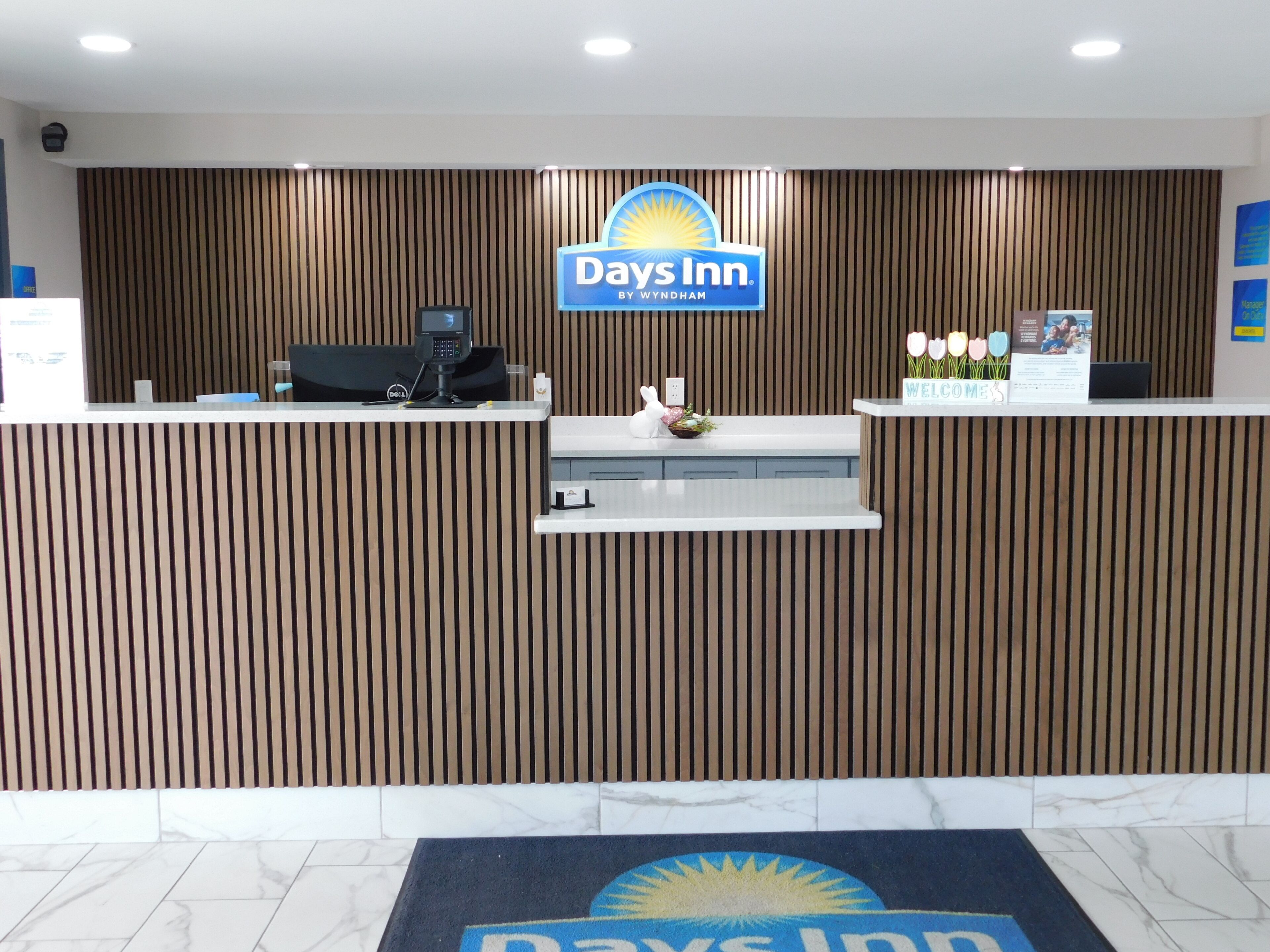 A reception desk with a Days Inn sign, a computer, and a small plant.