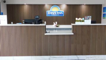 A reception desk with a Days Inn sign, a computer, and a small plant.
