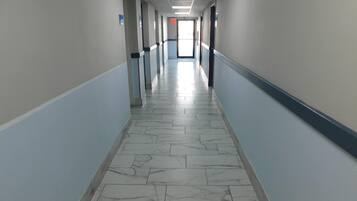 Un pasillo largo y estrecho con suelo de diseño de mármol y paredes azul claro.
