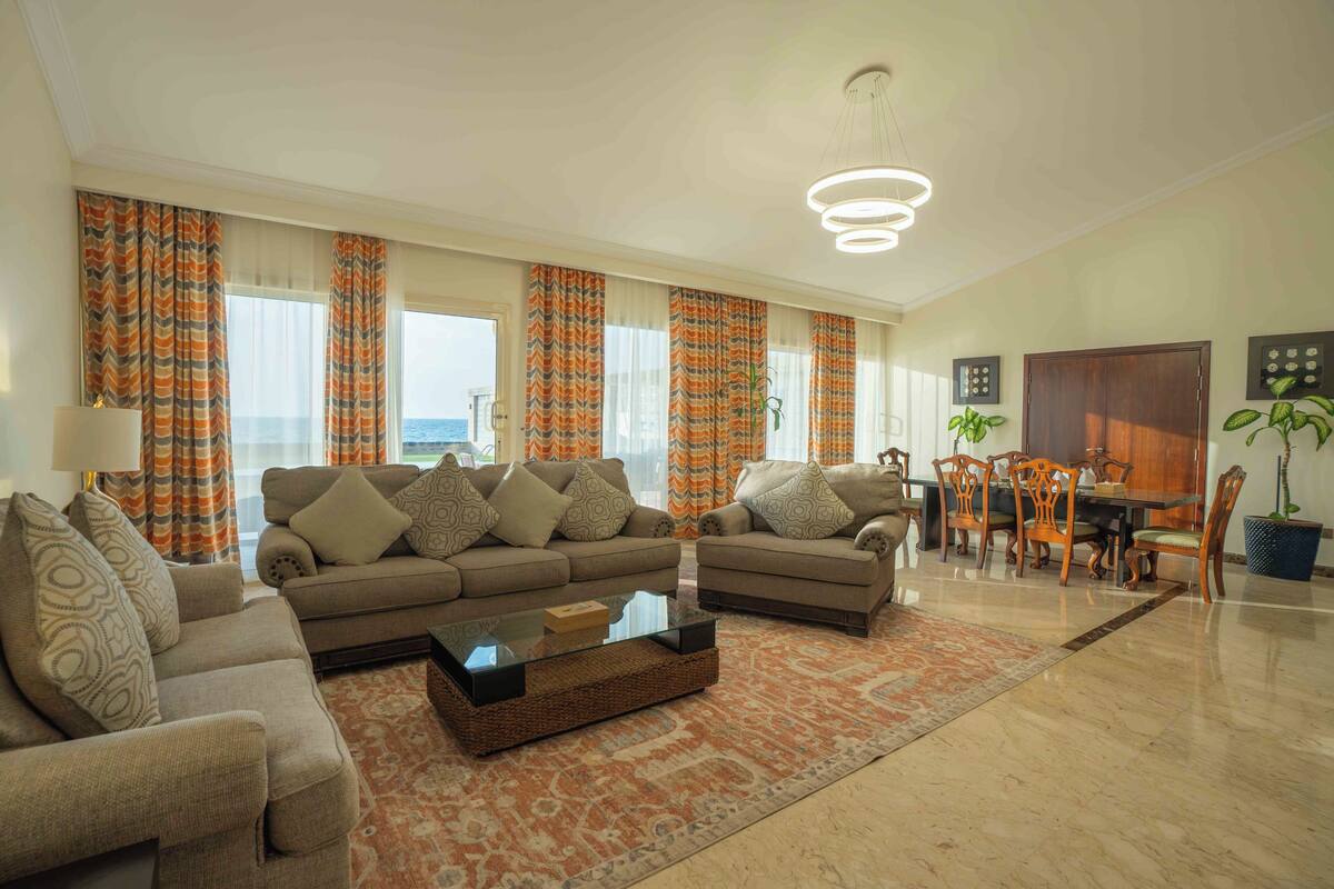 A spacious living room with two sofas, a coffee table, and a dining area with wooden chairs and a table.