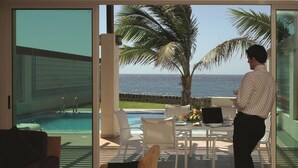 Una habitació amb piscina, una taula amb un ordinador portàtil i vista a l'oceà.