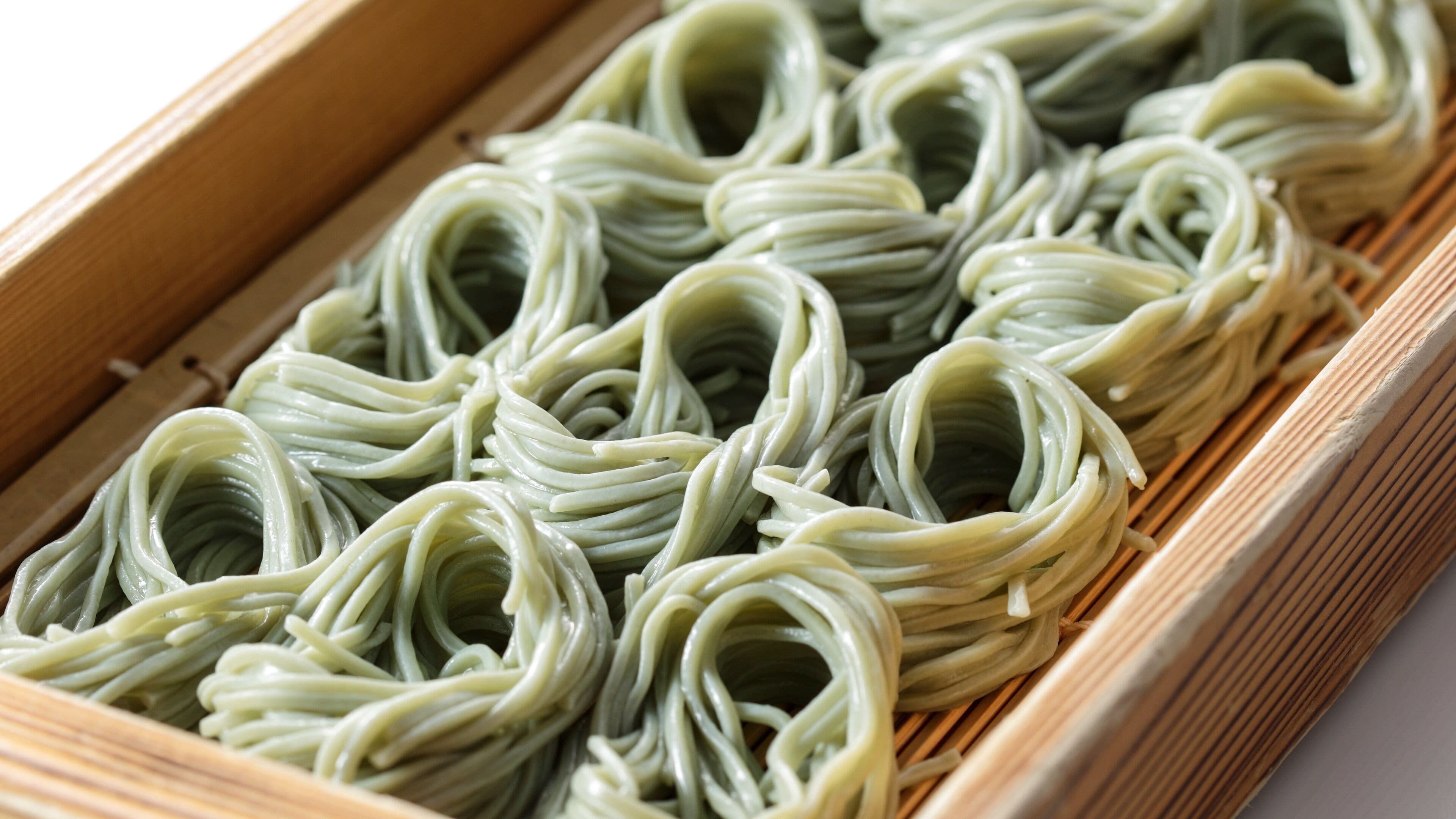 A tray of green noodles arranged neatly in rows.
