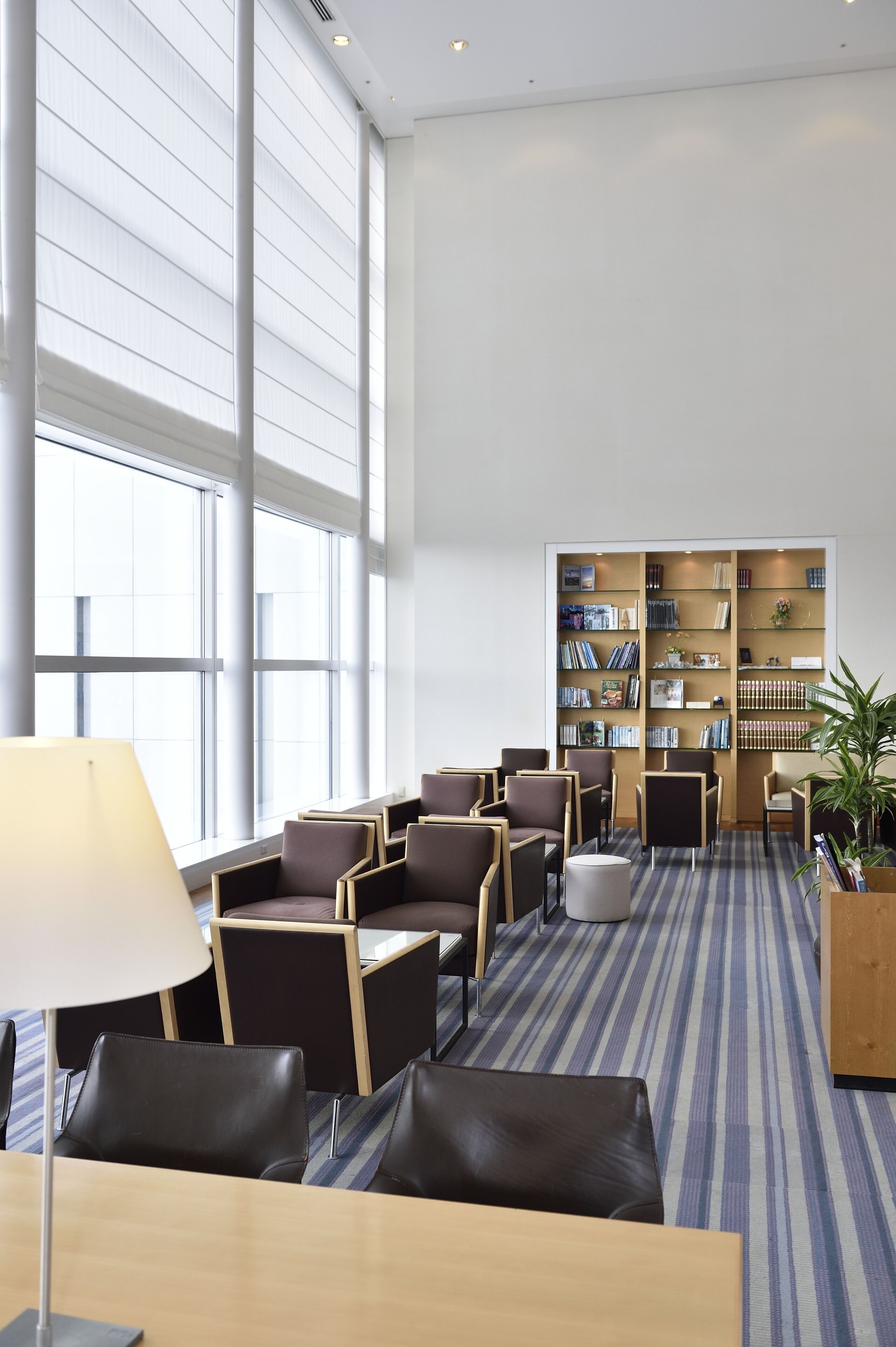 A modern library with bookshelves, comfortable seating, and large windows.