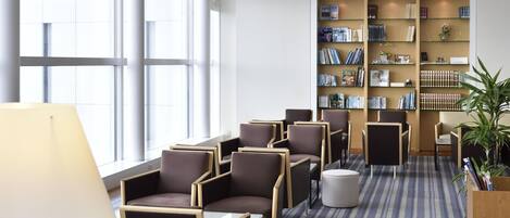 A modern library with bookshelves, comfortable seating, and large windows.