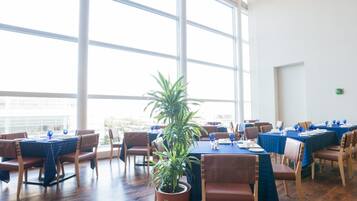 A conference room with large windows, wooden floors, and tables set for a meeting.