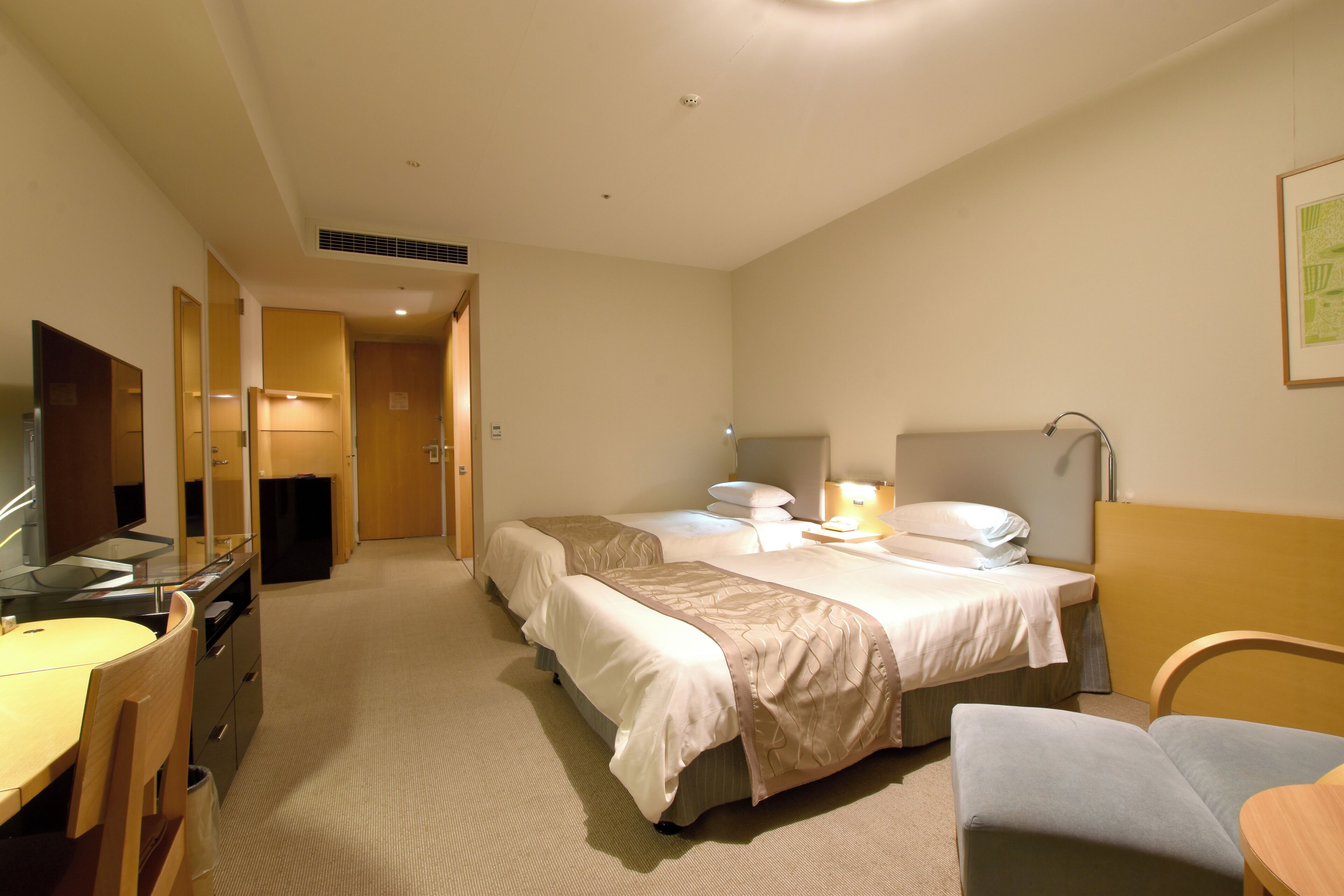 A hotel room with a bed, a desk, a chair, and a mirror.