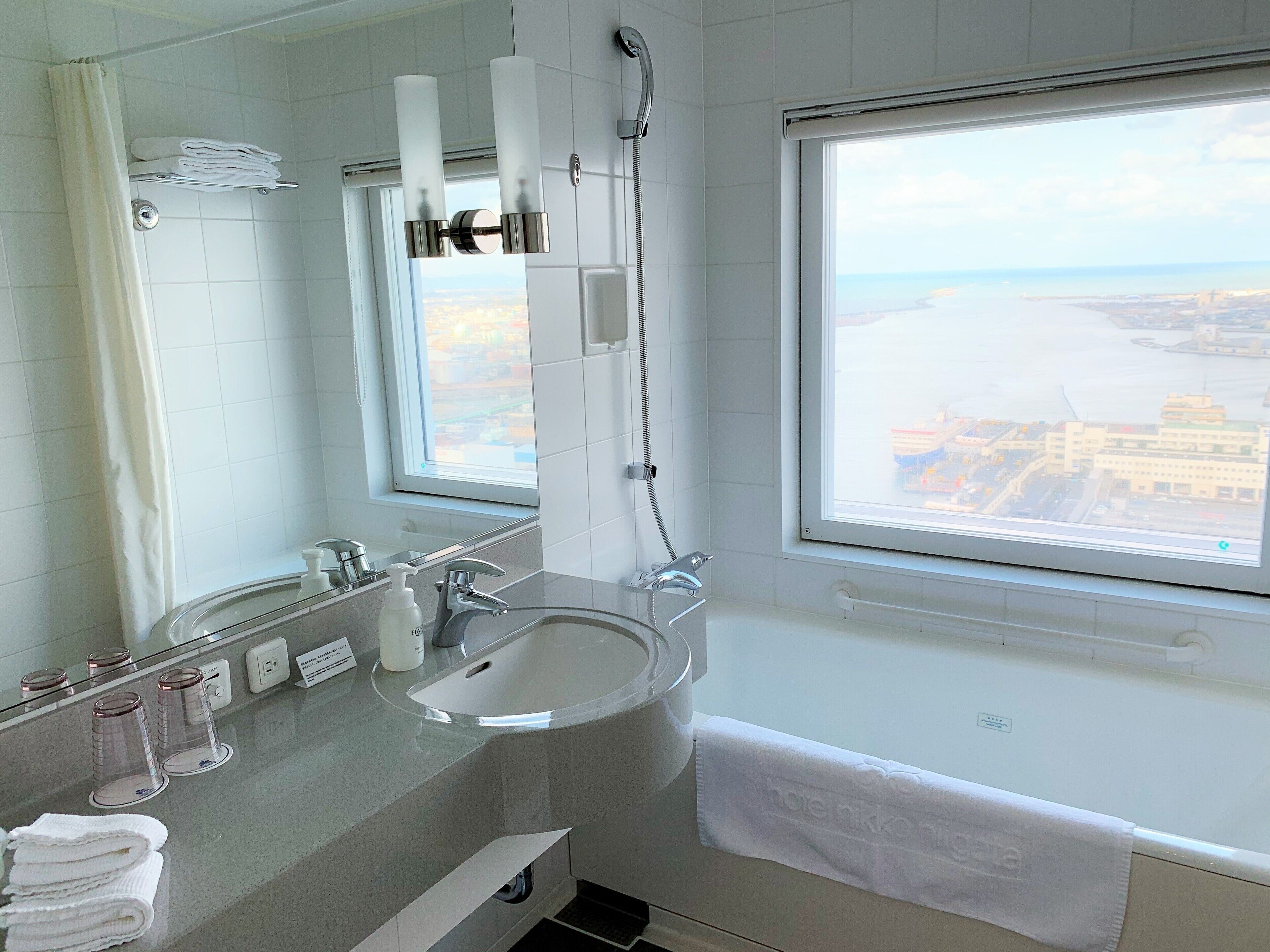 A modern bathroom with a large window, a sink, and a shower.