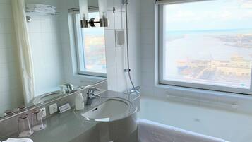 A modern bathroom with a large window, a sink, and a shower.