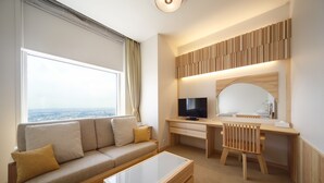 A modern living room with a sofa, coffee table, and a desk with a computer and TV. - Hotel Nikko Niigata (Niigata)