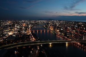 Vista aérea nocturna de una ciudad con un río, puentes y edificios iluminados.