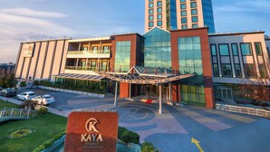 Un hotel moderno con una fachada de vidrio destacada, una entrada central con toldo y el letrero del hotel Kaya Istanbul.