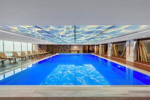 Relax by the pool surrounded by a unique ceiling design and comfortable sun loungers.