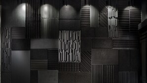 A modern interior with a bench and a wall featuring various geometric patterns and textures.