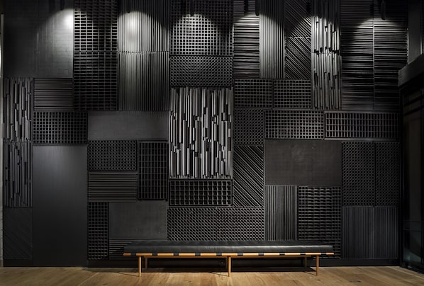 A modern interior with a bench and a wall featuring various geometric patterns and textures.