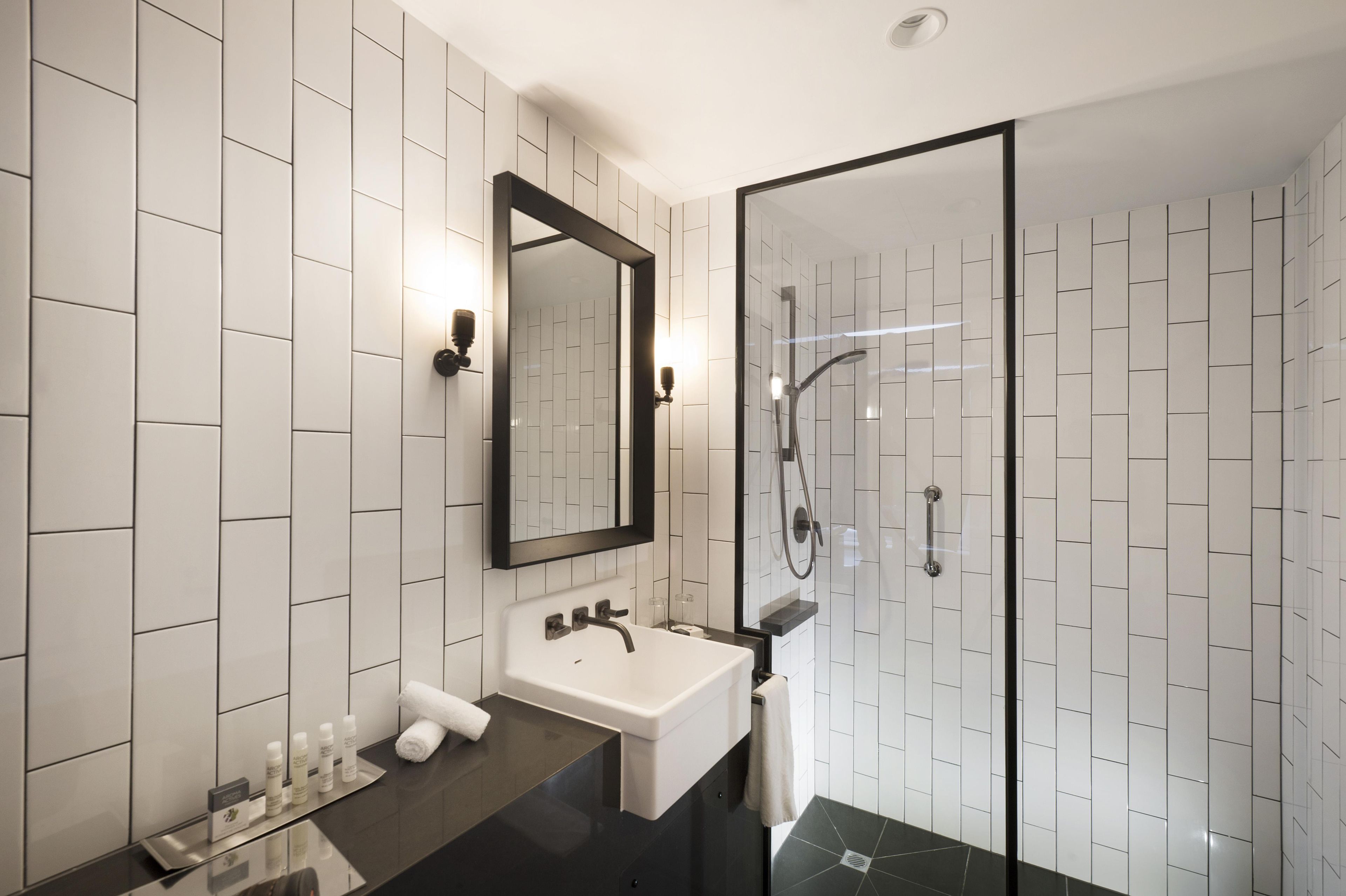 Un baño moderno con cabina de ducha de vidrio, un lavabo blanco y un espejo grande.