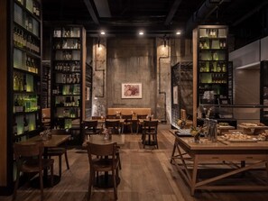 A restaurant interior with wooden tables and chairs, a central seating area, and shelves with bottles. - DoubleTree by Hilton Hotel Melbourne - Flinders Street (Melbourne)