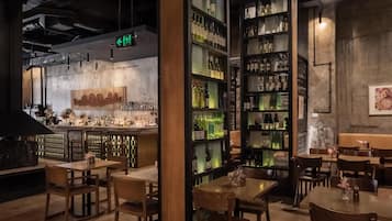 Una zona de bar con mostrador, estantes llenos de botellas y mesas y sillas de madera.