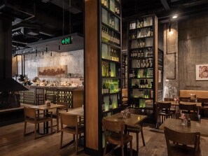 Una zona de bar con mostrador, estantes llenos de botellas y mesas y sillas de madera.