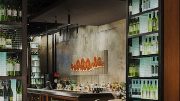 Una zona de bar con estantes llenos de botellas, muebles de madera y un letrero de neón.
