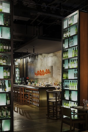 A bar area with shelves of bottles, wooden furniture, and a neon sign. - DoubleTree by Hilton Hotel Melbourne - Flinders Street (Melbourne)