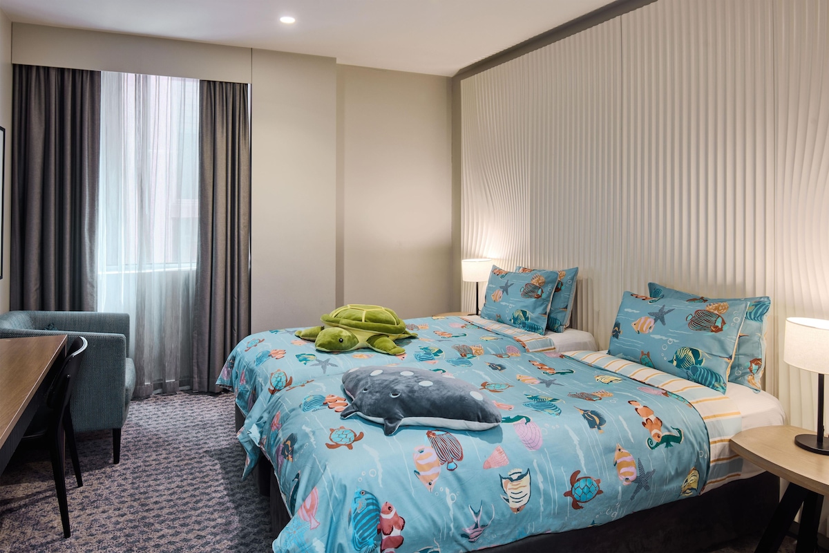 A hotel room with a bed, a desk, and a chair.
