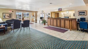 A hotel lobby with a reception desk, seating area, and a patterned carpet. - Quality Inn & Suites Eldridge Davenport North (Eldridge)