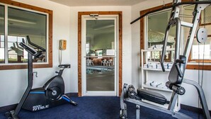 A gym with exercise equipment including a treadmill, stationary bike, and weight machines. - Quality Inn & Suites Eldridge Davenport North (Eldridge)