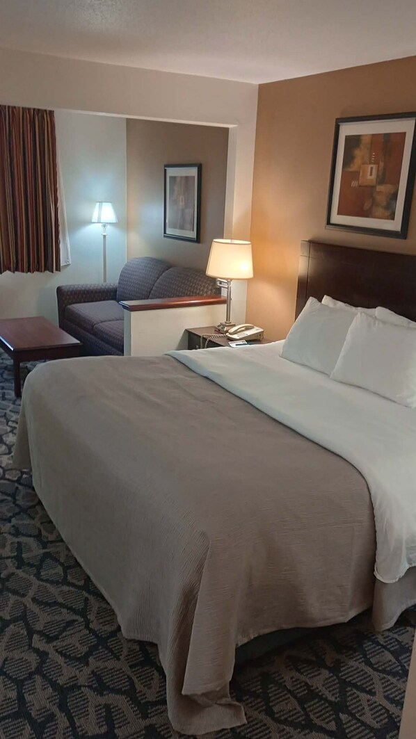 Una habitación de hotel con una cama grande, un escritorio con lámpara, una silla y un teléfono.