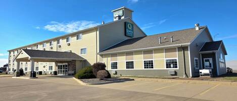 Un hôtel doté d’une entrée couverte, d’une enseigne indiquant « Quality Inn Suites » et d’un parking.