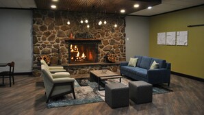 Un espace salon accueillant avec une cheminée en pierre, des sièges confortables et un design moderne au niveau du plafond.