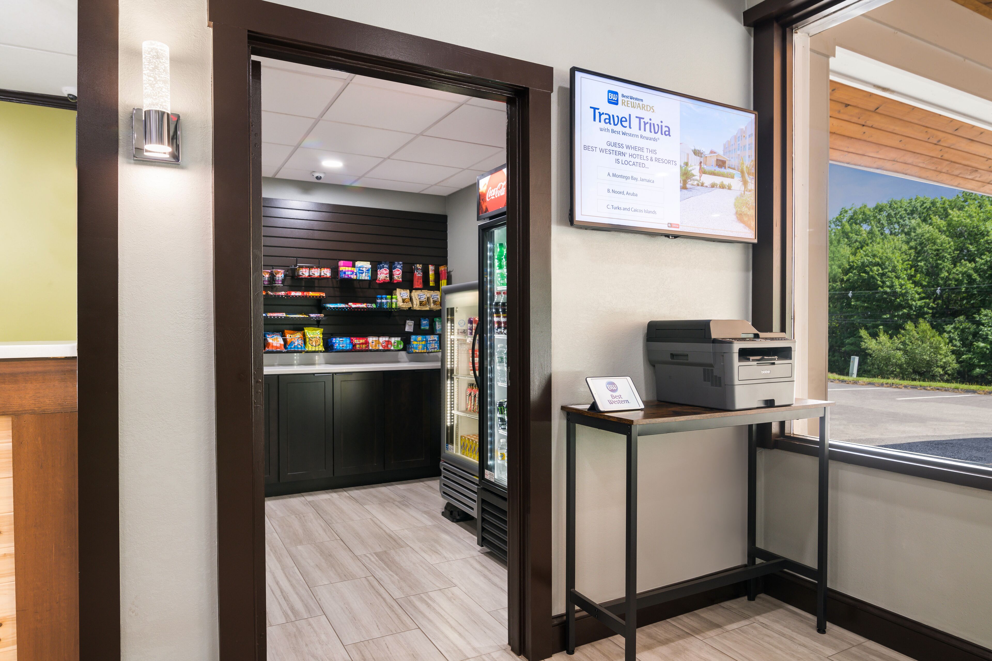 A hotel lobby with a Coca-Cola refrigerator, a vending machine, and a sign advertising travel rewards.