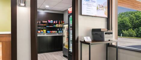 Un hall de hotel con un refrigerador de Coca-Cola, una máquina expendedora y un cartel que anuncia recompensas por viajar.