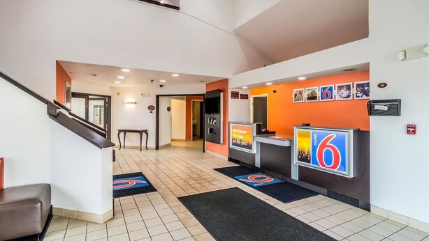 Un hall de hotel con una recepción, una escalera y un piso de baldosas.