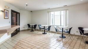 Una habitación amplia con piso de baldosas, un ventanal grande y un mostrador con sillas.