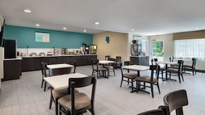 A modern dining area with tables and chairs, a kitchen counter, and a view of the outdoors. - Garner Hotel Londonderry - Manchester by IHG (Londonderry)