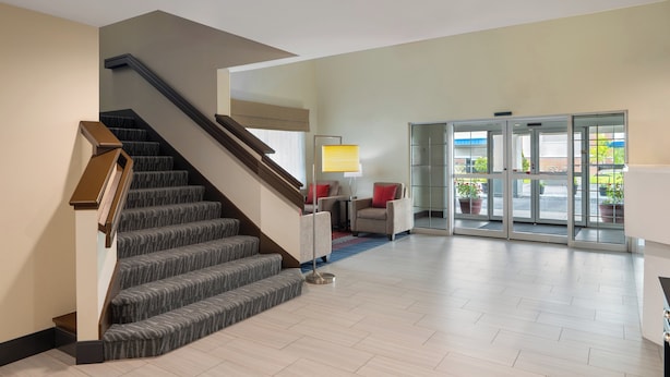A modern lobby with a staircase, a seating area, and a glass door entrance. - Garner Hotel Londonderry - Manchester by IHG (Londonderry)