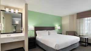 A hotel room with a bed, bedside tables, a mirror, a small table, and a chair. - Garner Hotel Londonderry - Manchester by IHG (Londonderry)