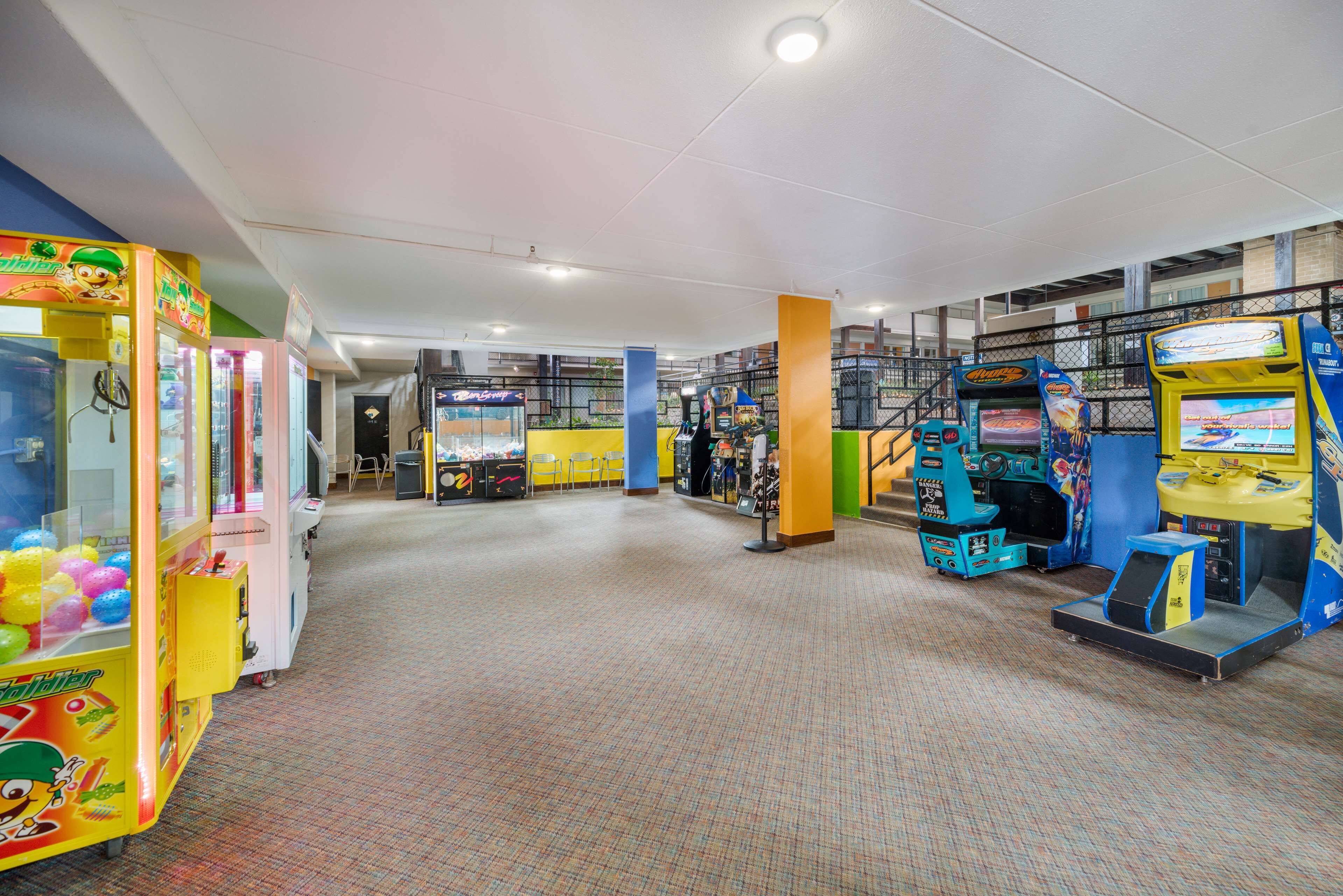 Un grand espace intérieur comprenant de nombreuses bornes d’arcade et des distributeurs automatiques, proposant une variété de jeux et d’en-cas.