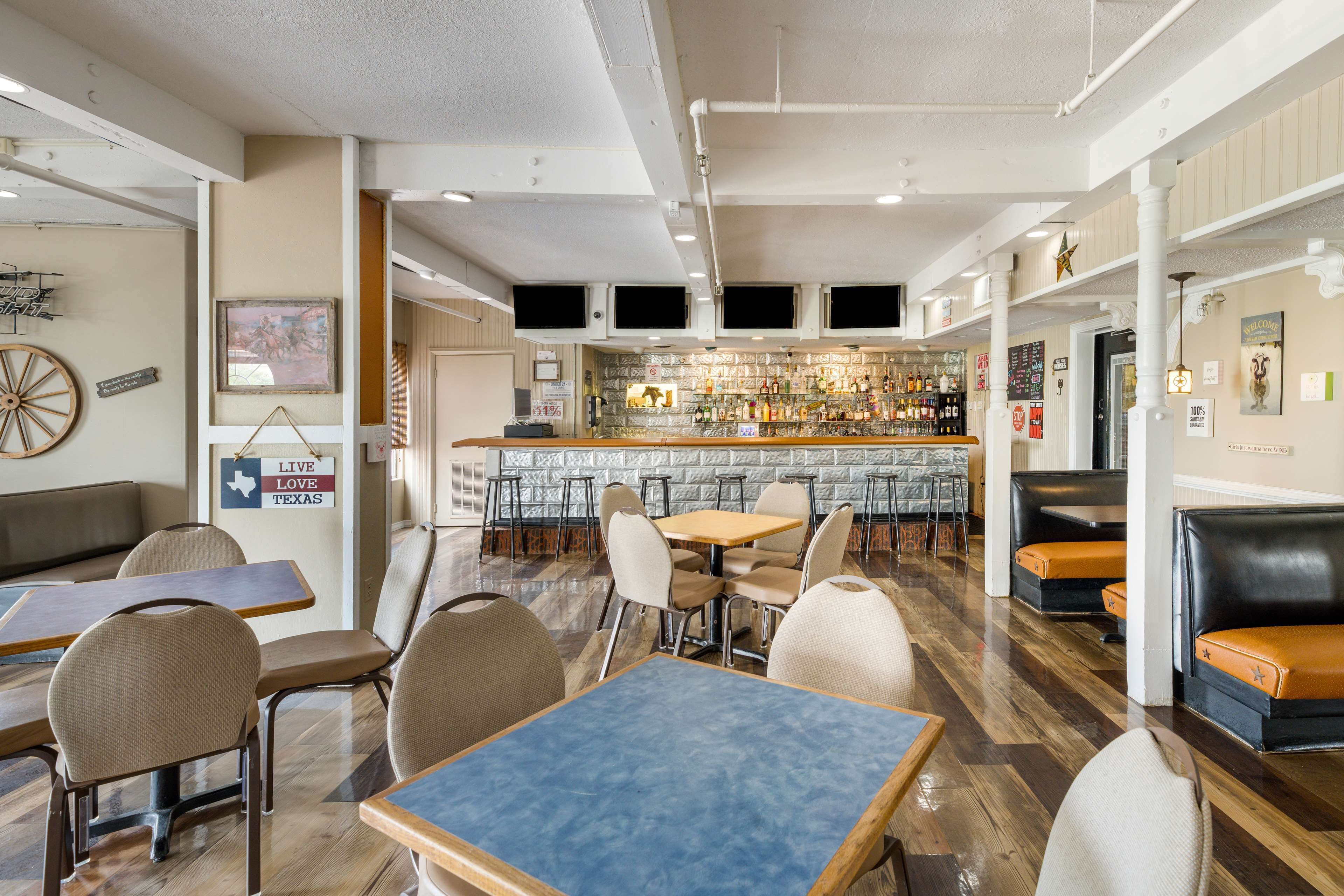 A restaurant with a bar area, seating arrangements, and a wall with a sign.