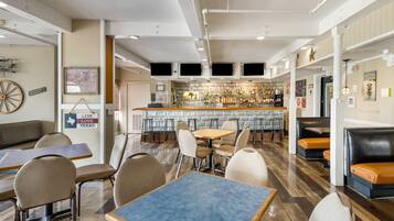 A restaurant with a bar area, seating arrangements, and a wall with a sign.