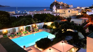 A swimming pool with lounge chairs and umbrellas, surrounded by greenery and buildings. - Hotel Villa Durrueli Resort & Spa (Ischia)