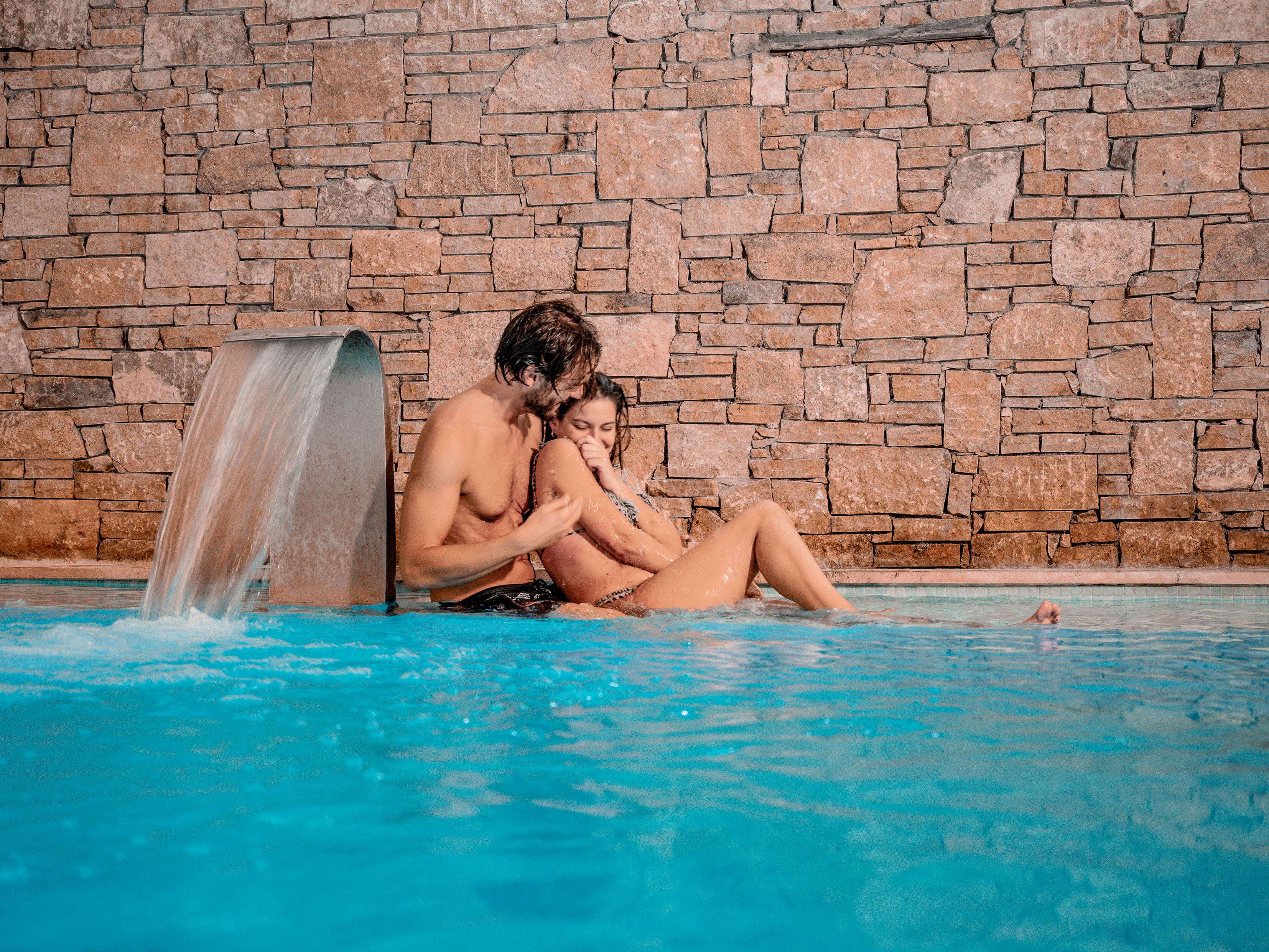 A stone wall and a pool with a waterfall feature.