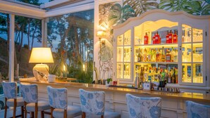 A bar area with a glass display case containing bottles and glasses, surrounded by bar stools. - Secret Paradise Hotel & Spa (Nea Propontida)