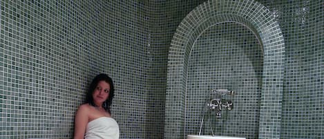 A bathroom with a tiled floor, a sink, and a bench.