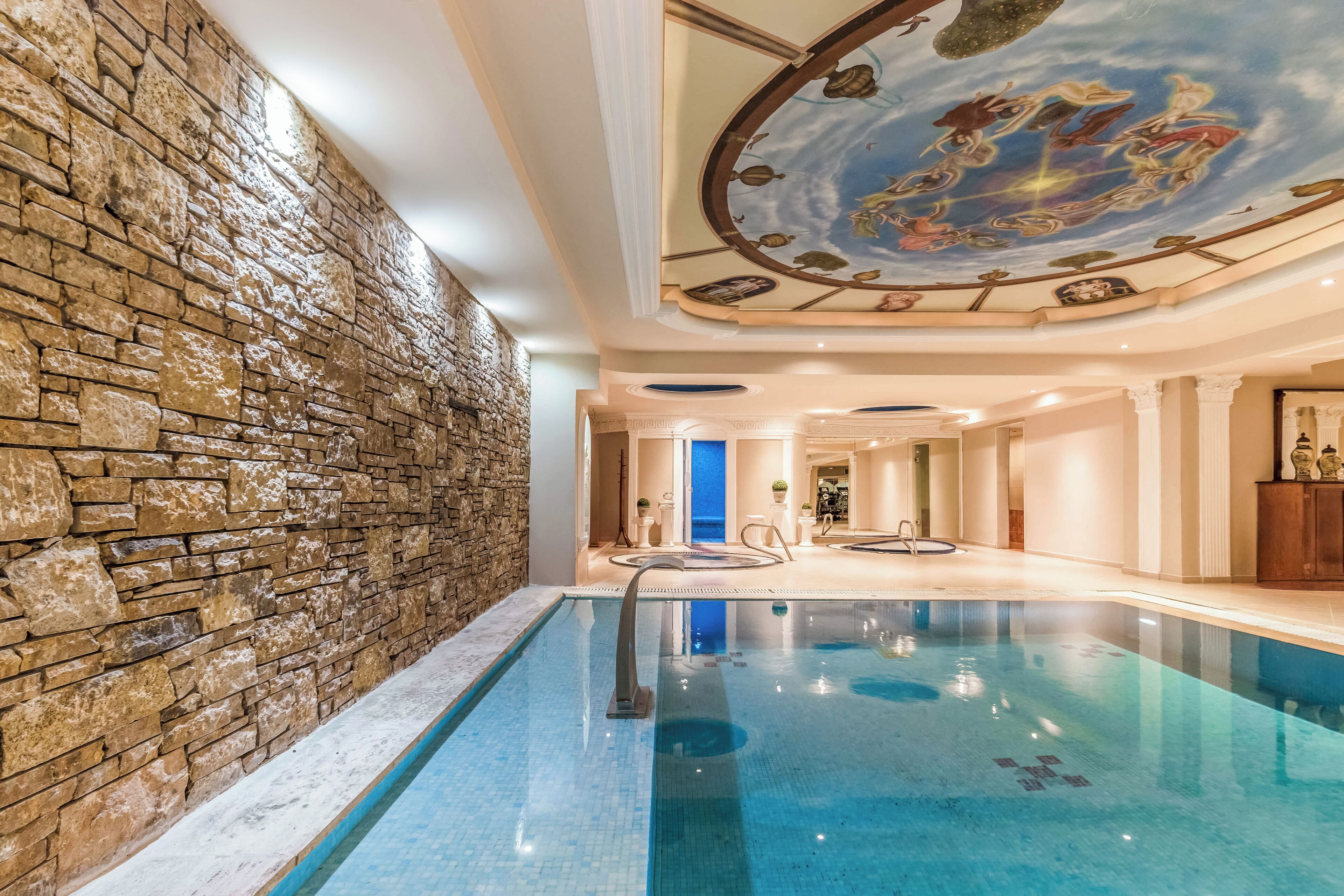 Ein Innenpool mit Steinwand und Deckenfresko.
